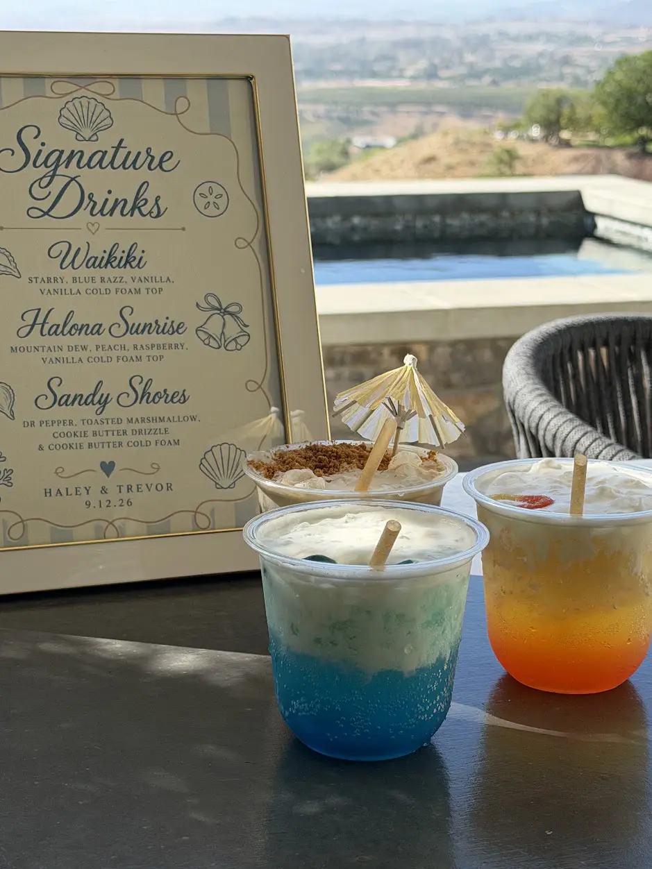 Signature drink menu sign beside three layered craft sodas with paper umbrellas at a private engagement dinner