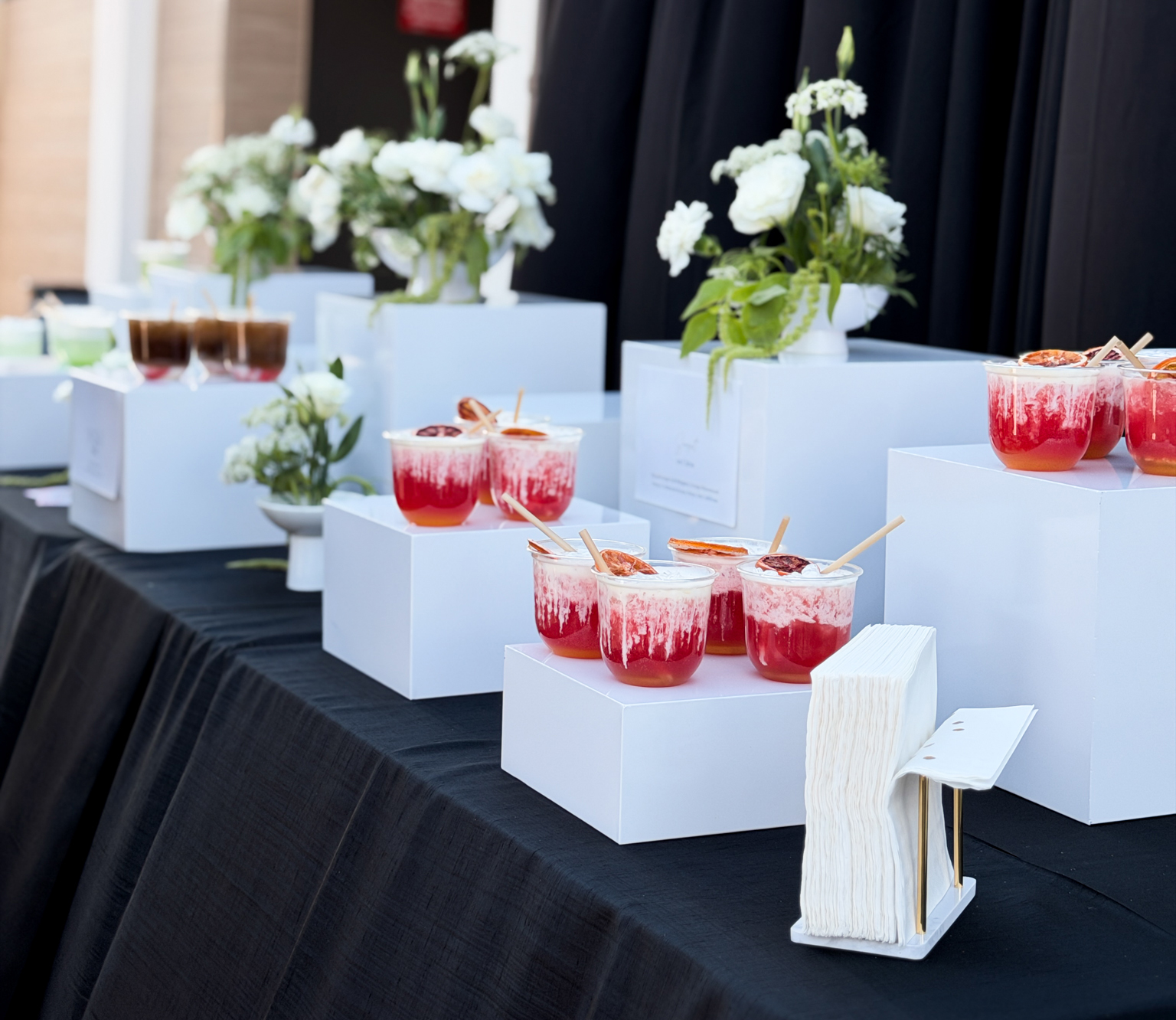 Corporate event bar setup with craft dirty sodas and white floral arrangements