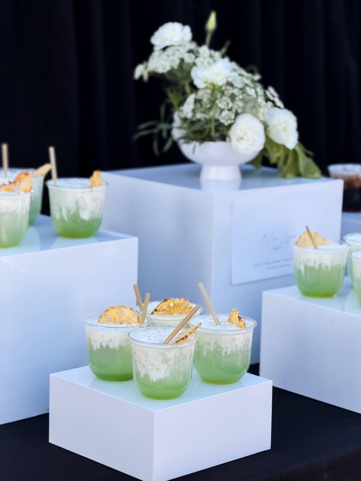 Matcha pineapple mocktails displayed on white pedestals at corporate event