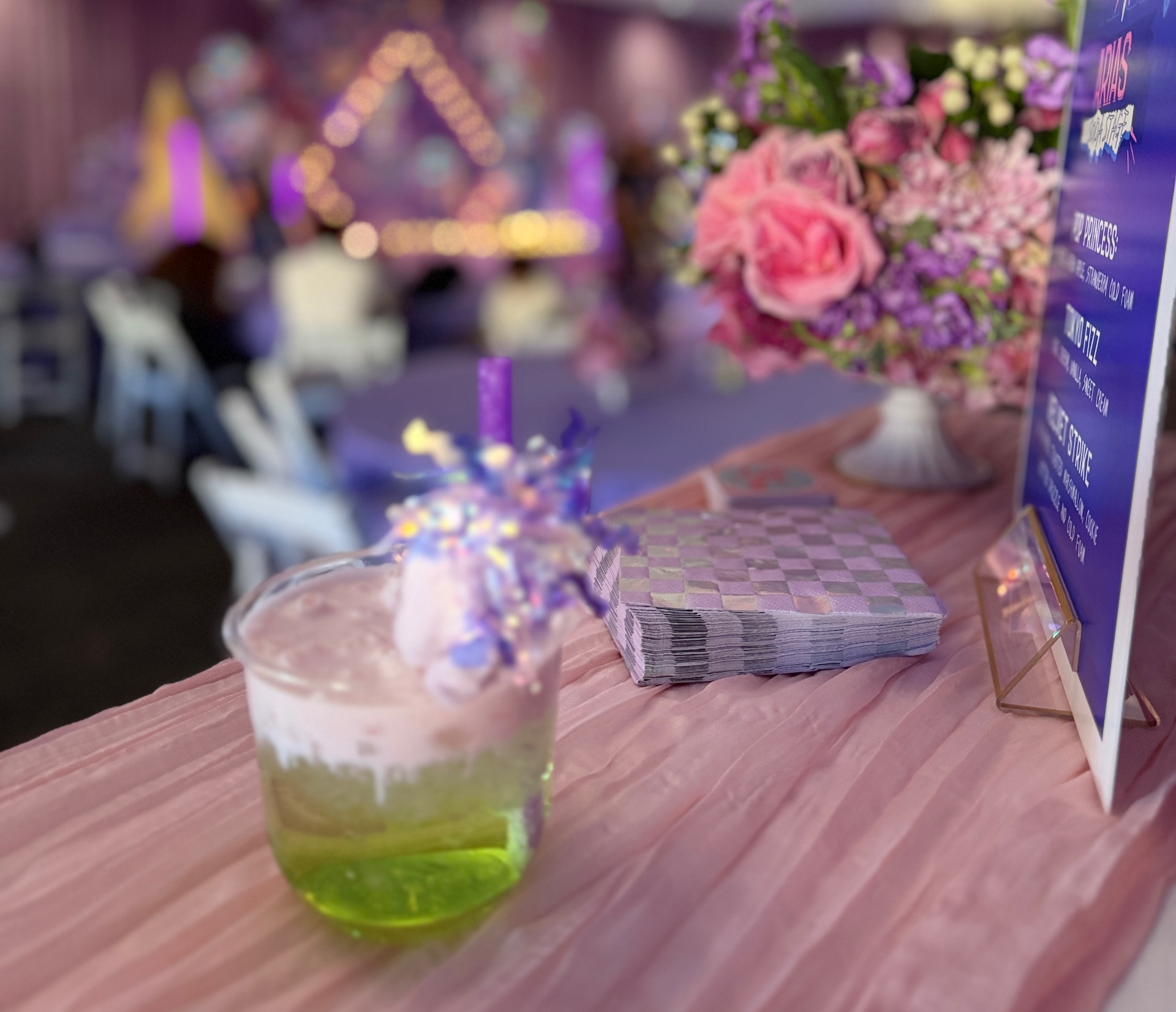 Colorful party mocktail with cotton candy topper on a pink draped table
