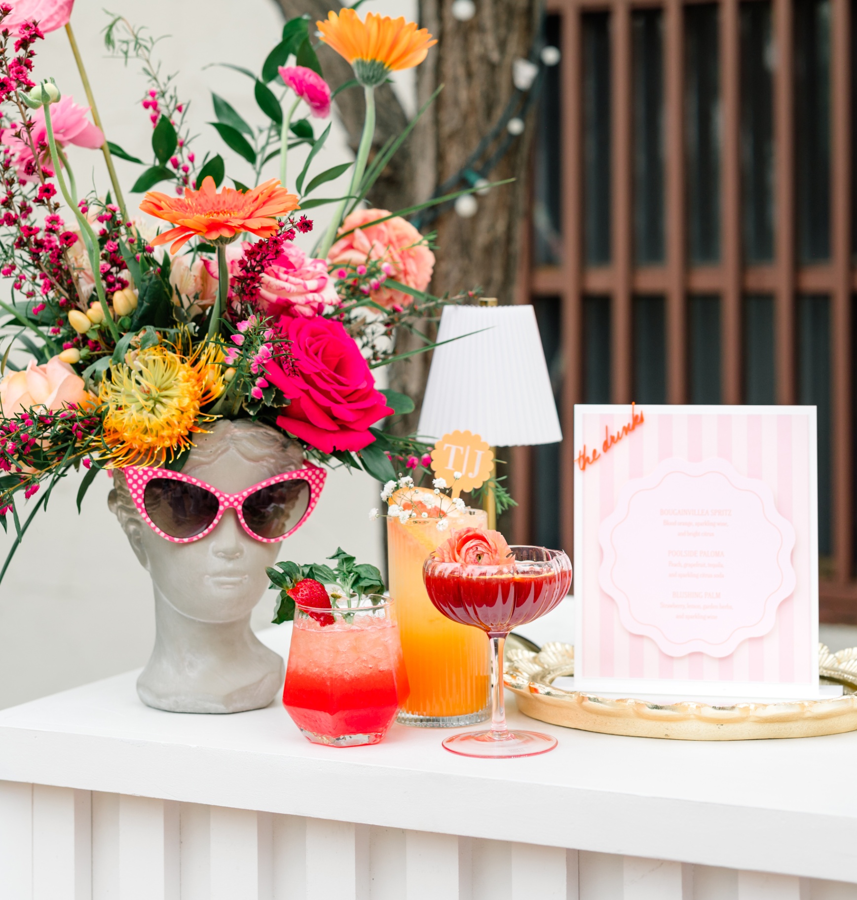 Styled mocktail bar with floral arrangement, custom drink menu, and signature pink drinks at an Inland Empire wedding